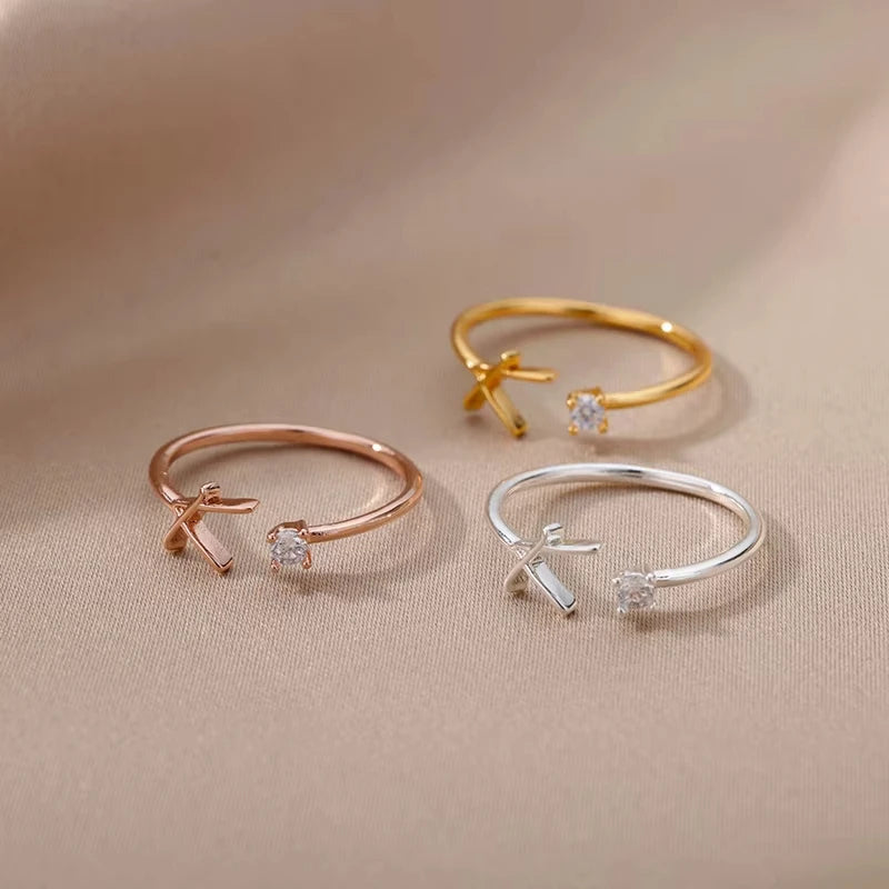 Three elegant open rings in gold, rose gold, and silver finishes, each featuring a delicate crystal accent and a sleek minimalist design, embodying the refined style of Infinity.